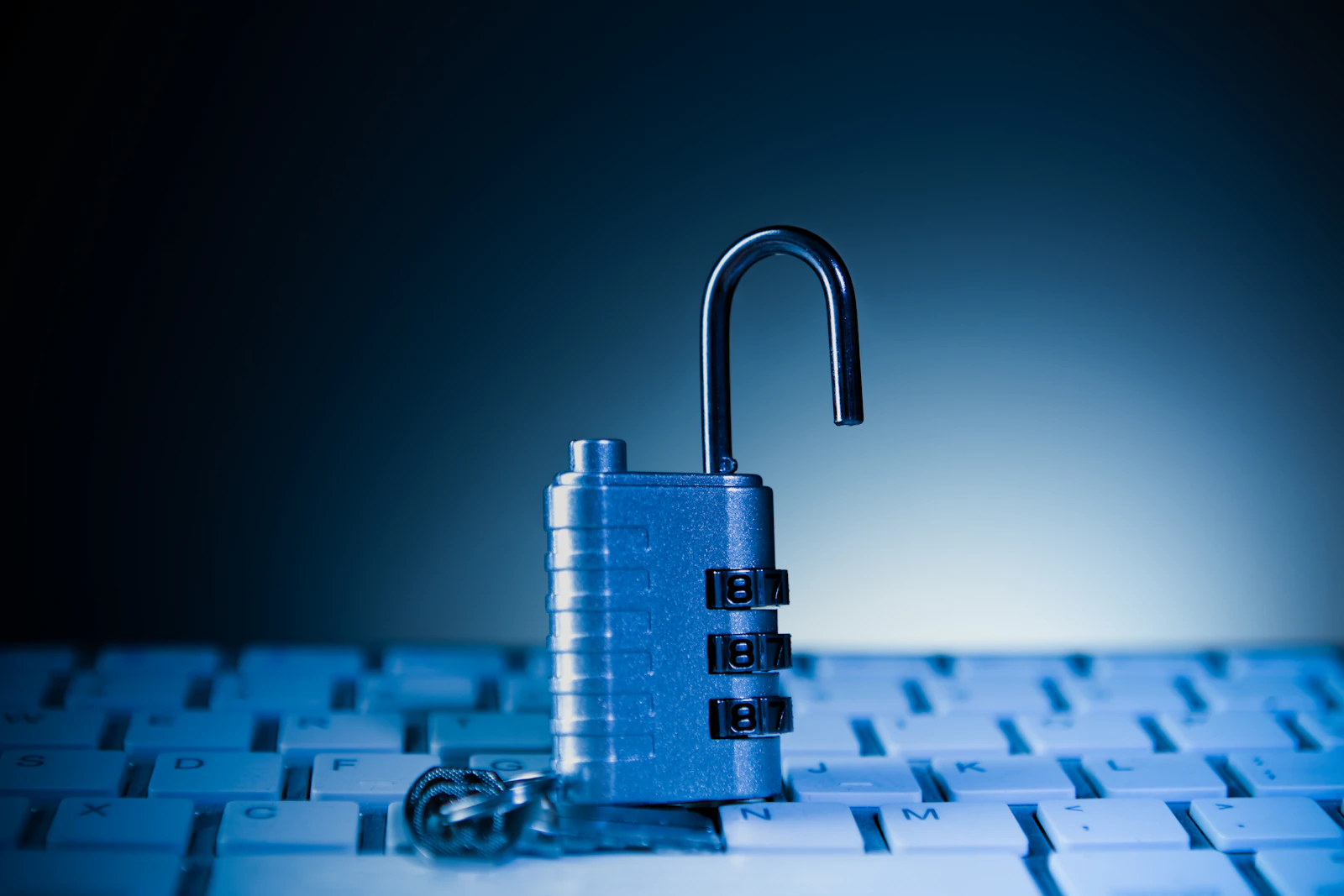 Open combination padlock on a computer keyboard, illustrating business cybersecurity and data protection